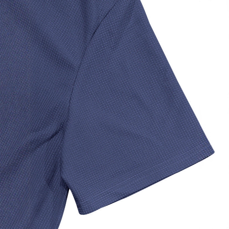 Primer plano de manga de polo azul para hombre en tejido gofrado transpirable, detalle de textura waffle.