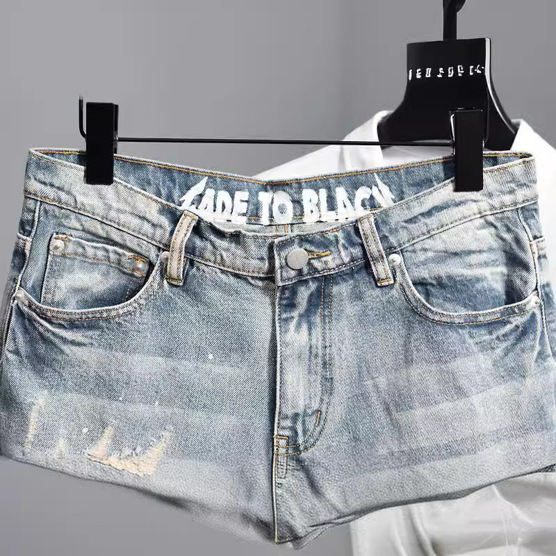 Pantalón corto vaquero de hombre con efecto desgastado y texto interior en la cintura sobre fondo gris.