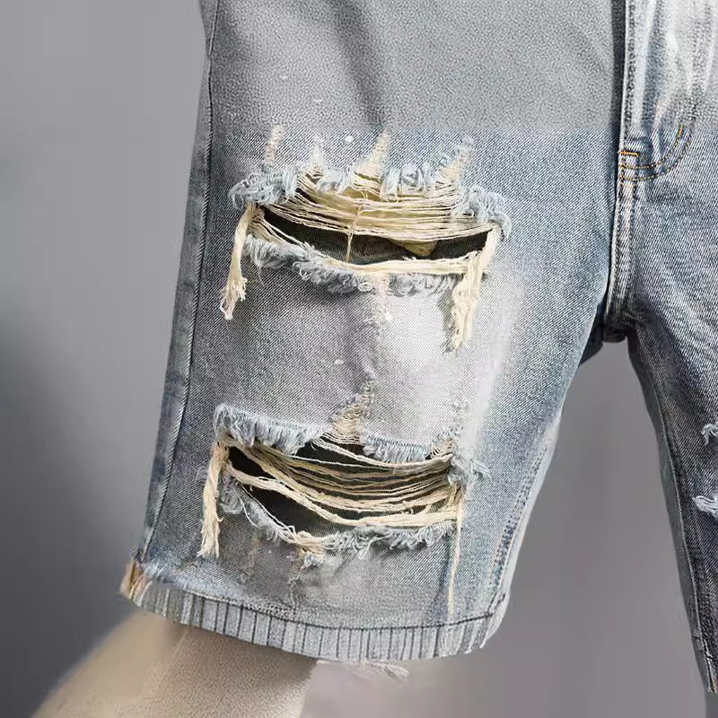 Detalle de rotos y desgastes en pantalones cortos vaqueros para hombre de corte recto en azul claro.