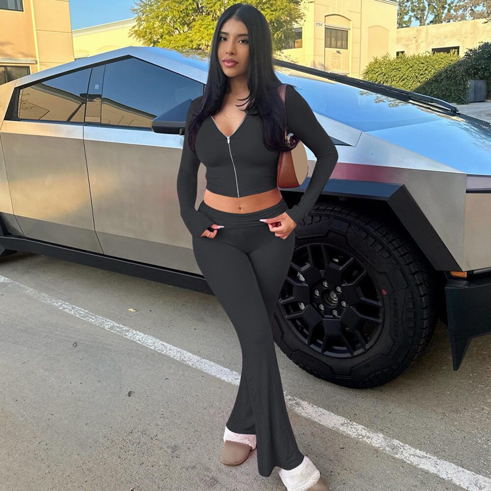 Chándal de mujer negro con chaqueta corta de cremallera y pantalones acampanados de talle alto.