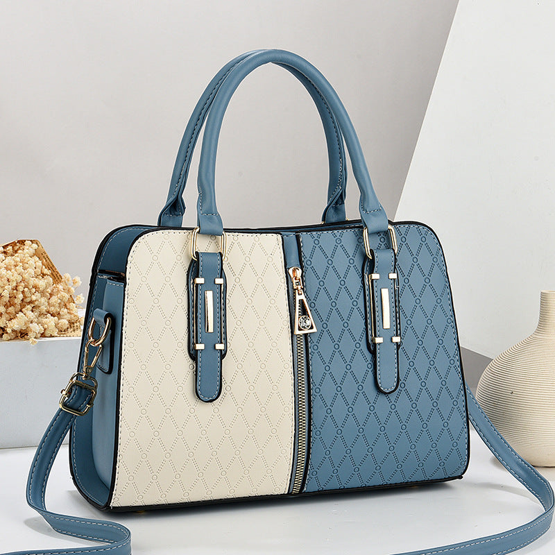 Bolso tote grande para mujer en color azul y crema con diseño color-block, textura grabada y detalles dorados.