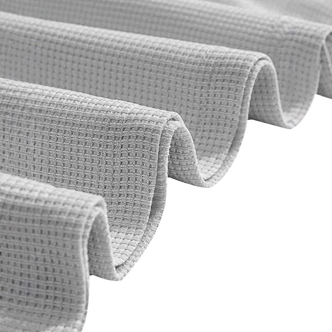 Primer plano de tela con textura waffle o gofrado en color gris claro, suave y transpirable para conjunto deportivo.